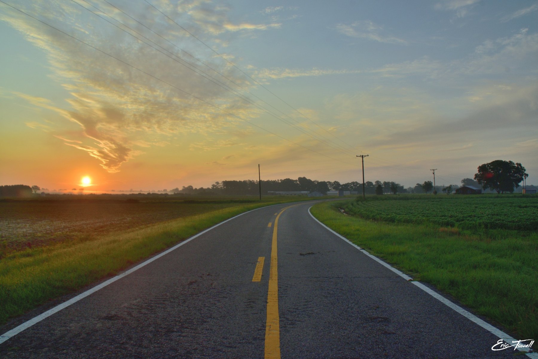 A country road curving through fields at sunrise